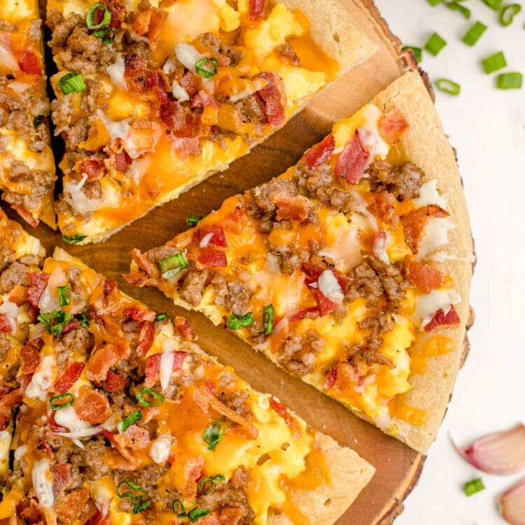 Overhead shot of breakfast pizza cut into slices on a wooden pizza board