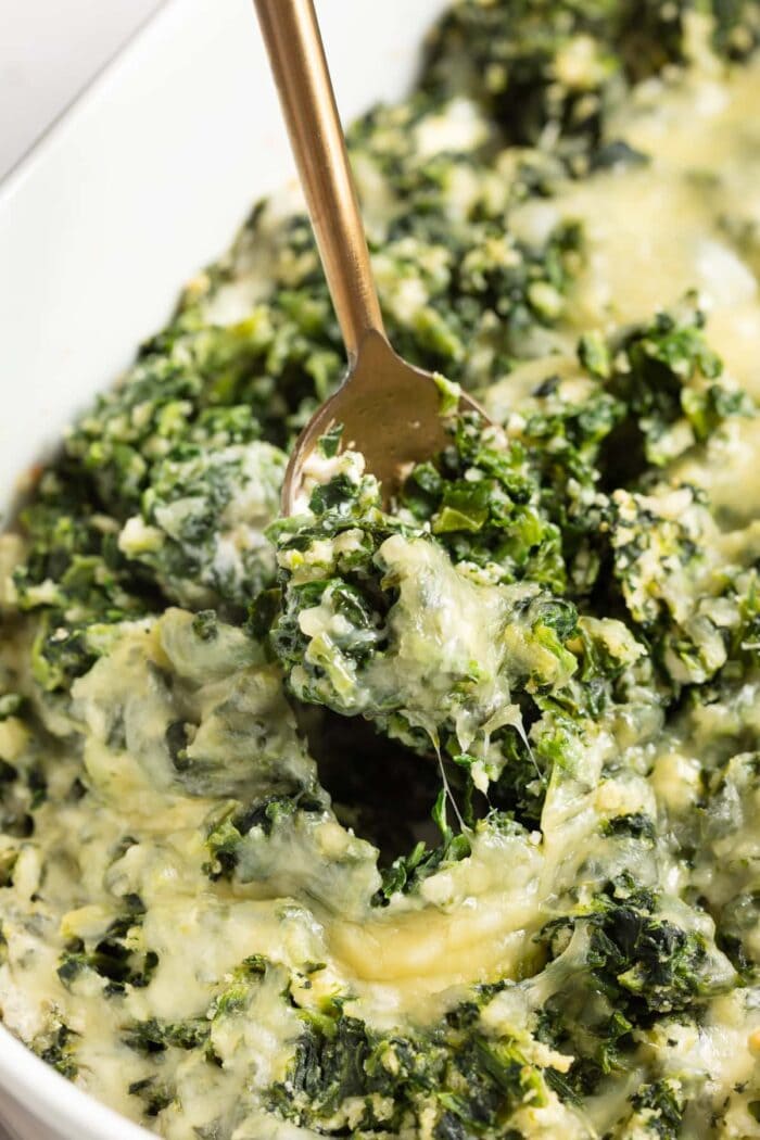 spinach casserole being scooped out of the baking dish