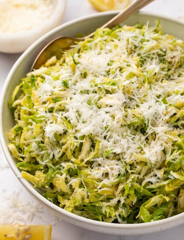 Angled side view of a bowl of shaved Brussels sprouts salad with lemon and parmesan