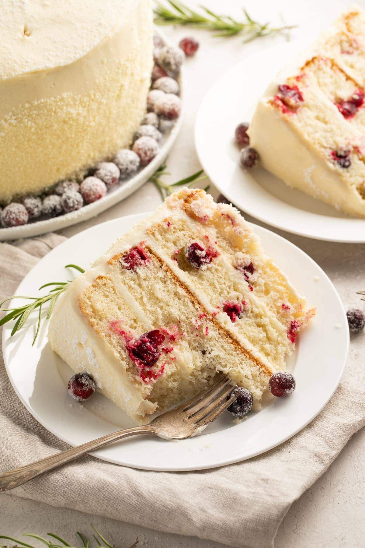 A slice of cranberry white chocolate cake on a white plate with a fork.