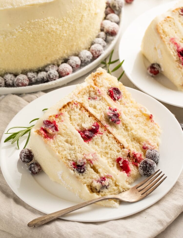A slice of cranberry white chocolate cake on a white plate with a fork.