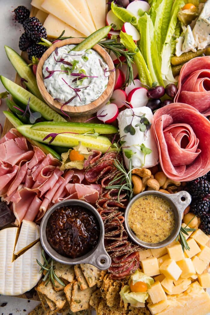 Close up view of keto charcuterie board with salami roses, dips, bacon jam, prosciutto, radishes, and cheeses