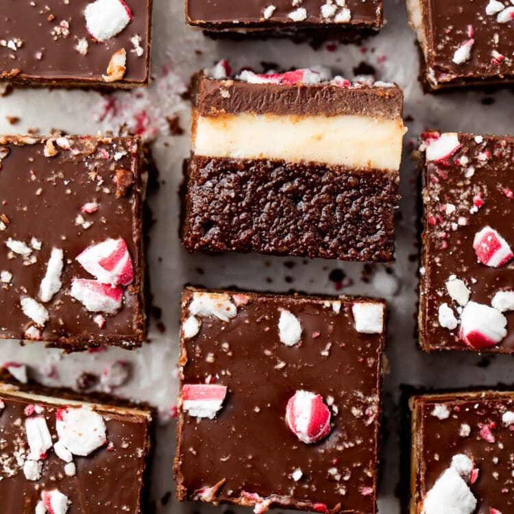 Overhead view of keto peppermint layer brownies on parchment paper, with the center brownie on its side so you can see the layers
