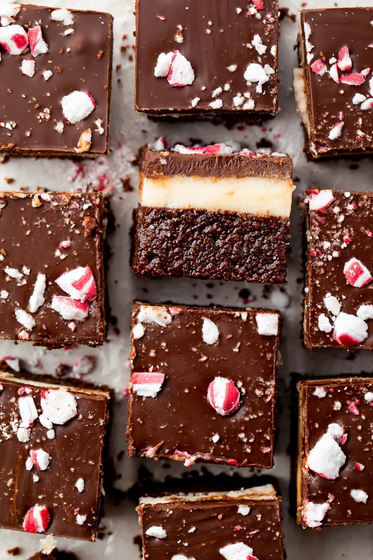 Overhead view of keto peppermint layer brownies on parchment paper, with the center brownie on its side so you can see the layers