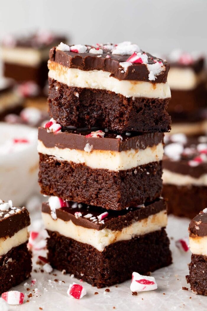 3 keto peppermint layer brownies stacked on top of each other, with a bite taken out of the brownie on top