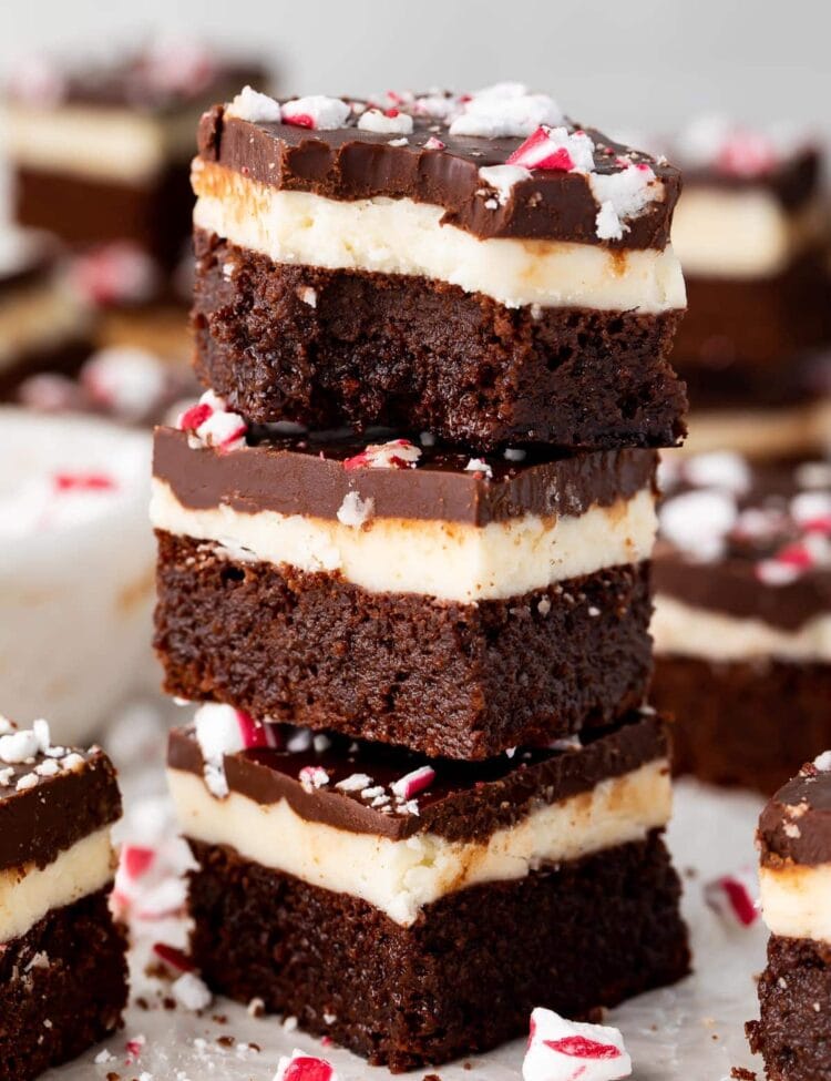 3 keto peppermint layer brownies stacked on top of each other, with a bite taken out of the brownie on top