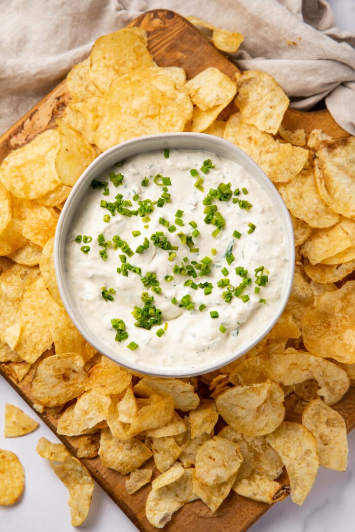 Overhead view of a bowl of clam dip surrounded by potato chips