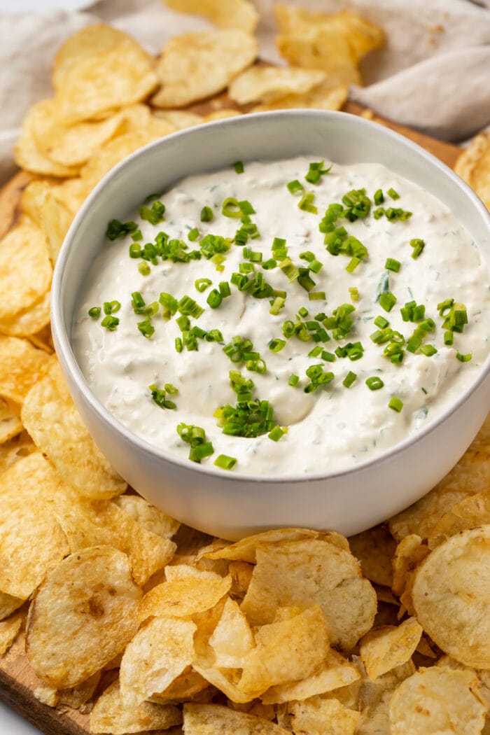 Clam dip in a white bowl with potato chips