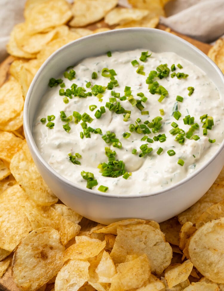 Clam dip in a white bowl with potato chips