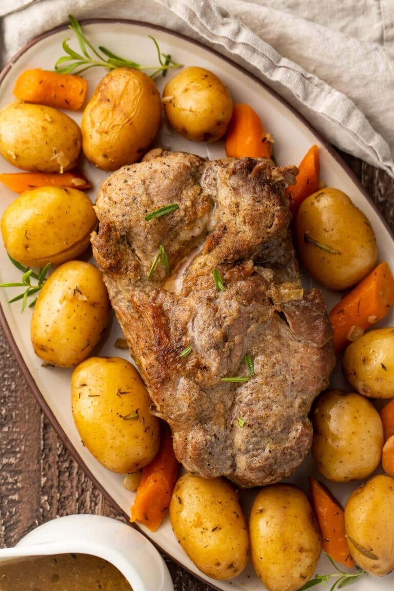 Instant Pot pork roast with carrots and potatoes on a large oval-shaped dish.