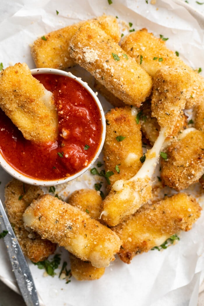 overhead image of air fryer mozzarella sticks on a plate with a side of marinara sauce