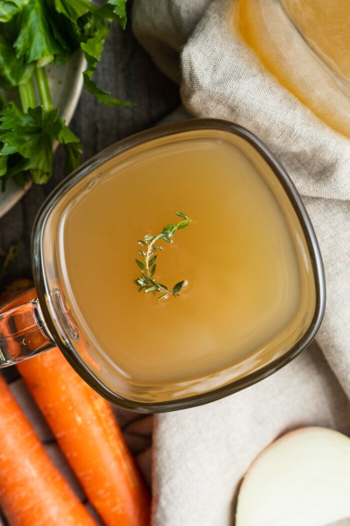 crockpot bone broth in a mug with fresh thyme on top