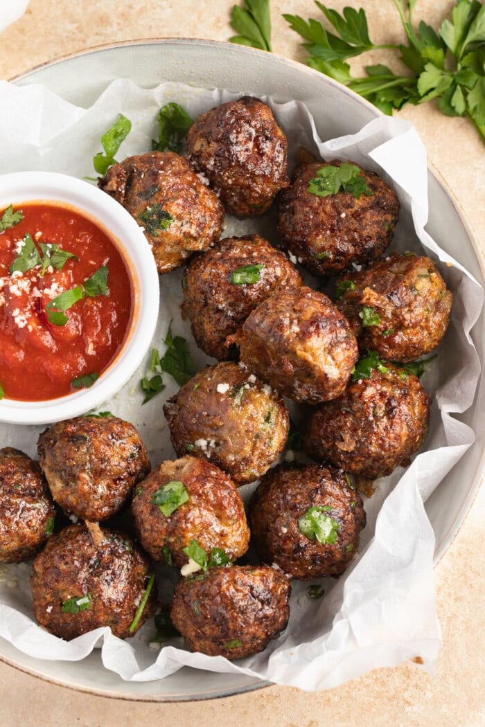 Air fryer meatballs on a plate with a ramekin of marinara sauce