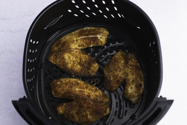 Cooked tilapia fillets in air fryer basket.