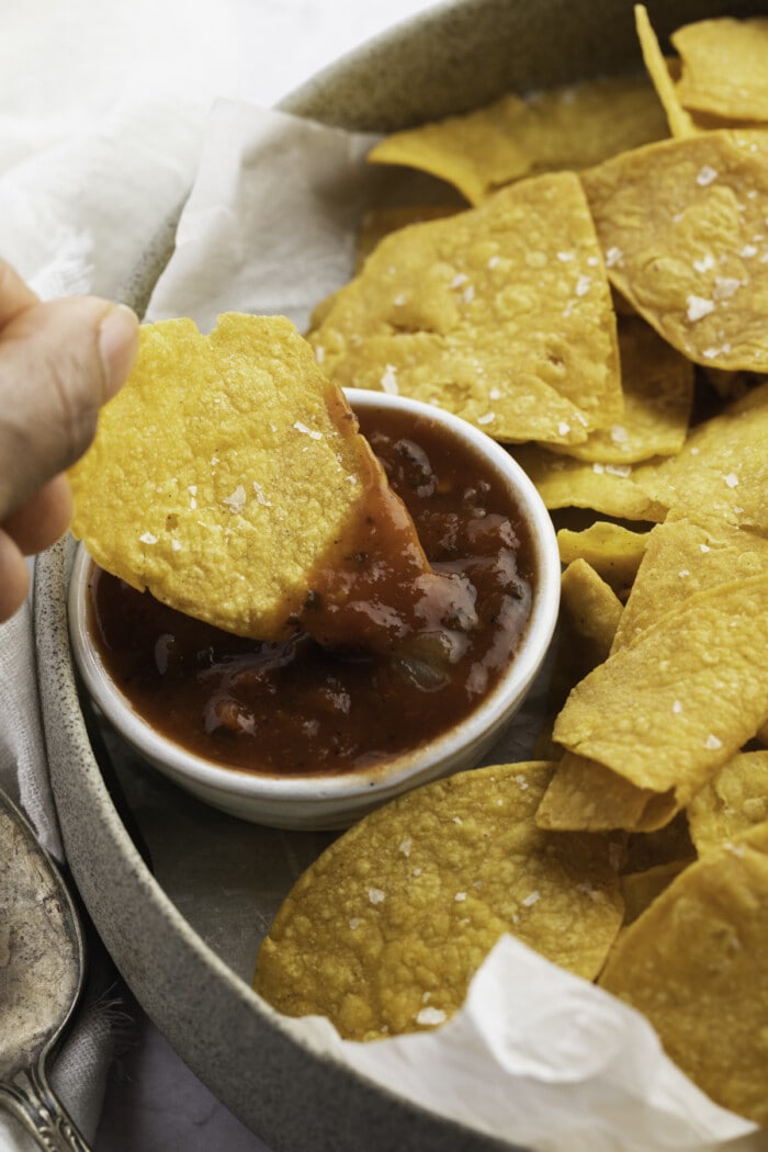 Air fryer tortilla chips dipped into a small bowl of salsa