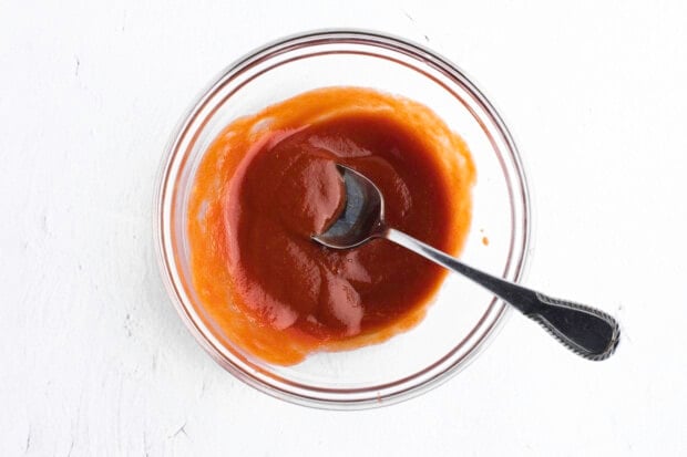 Paleo-friendly ketchup glaze in large glass bowl with metal spoon
