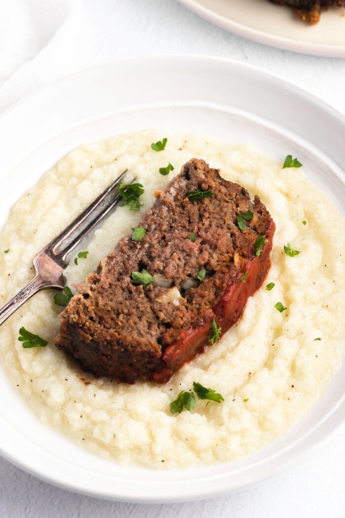 Overhead angled view of a slice of paleo meatloaf on a bed of mashed potatoes