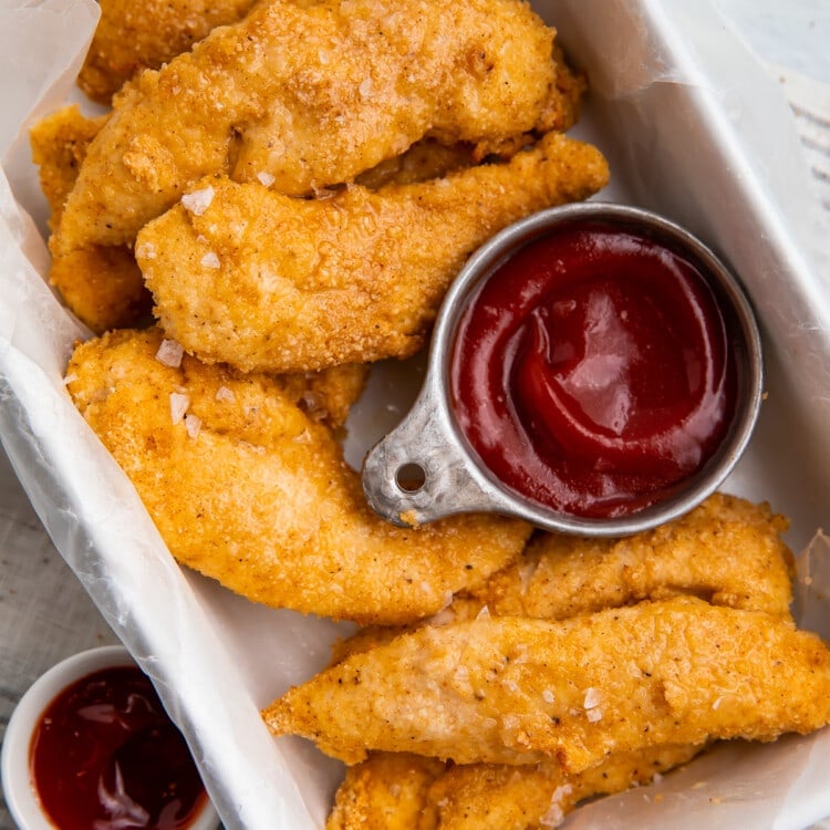 Whole30 chicken tenders in a baking dish with a compliant dipping sauce