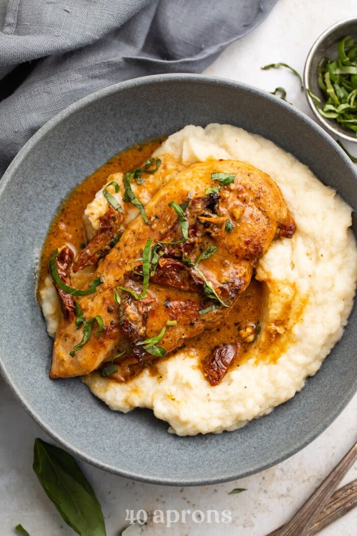 Whole30 marry me chicken in a blue-grey bowl with mashed potatoes