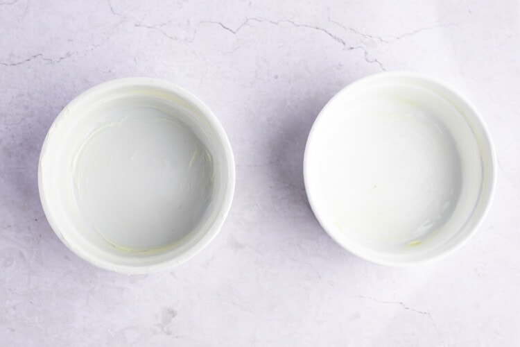 Overhead view of two white 10-ounce ramekins on a white background.