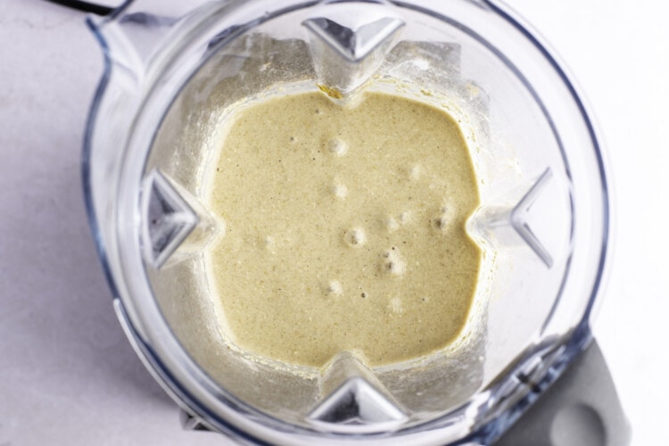 Overhead view of the oat and banana mixture in a blender on a white background.