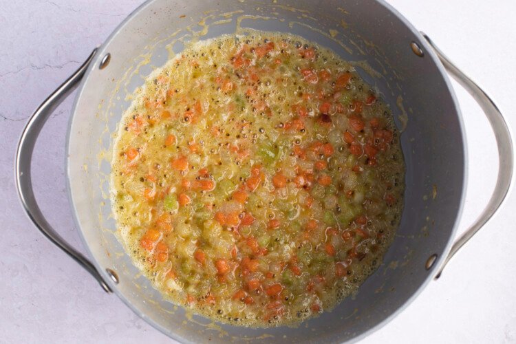 Mirepoix in heavy-bottomed pot on white background.