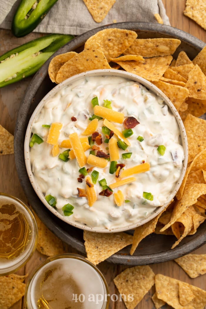 Overhead view of a bowl of jalapeno popper dip surrounded by tortilla chips