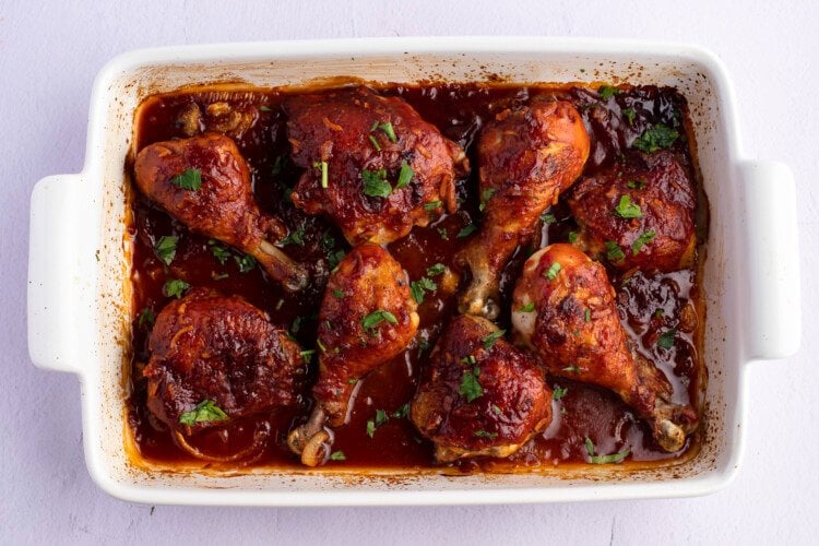 Overhead view of baked celebration chicken in a white 9x13 rectangular baking dish.