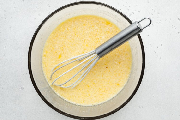 Overhead view of wet ingredients for gluten-free donuts in large glass bowl with whisk.