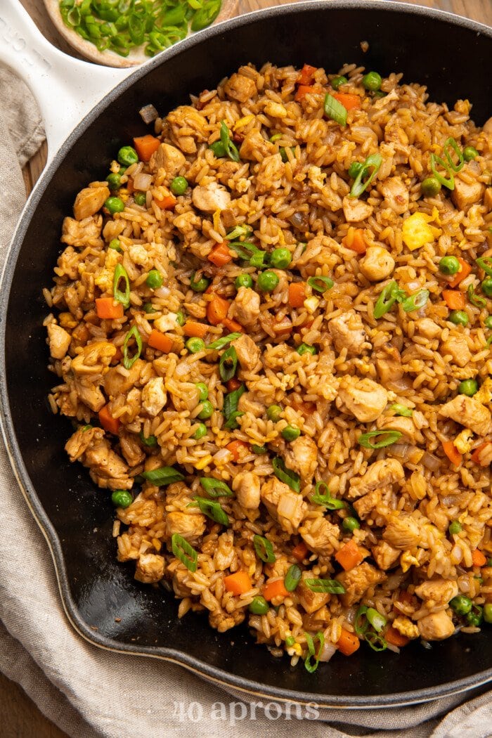 Overhead view of chicken fried rice in a large cast iron skillet.