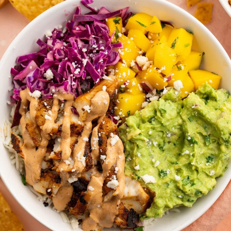 Overhead view of a fish taco bowl with mango salsa and red cabbage slaw.
