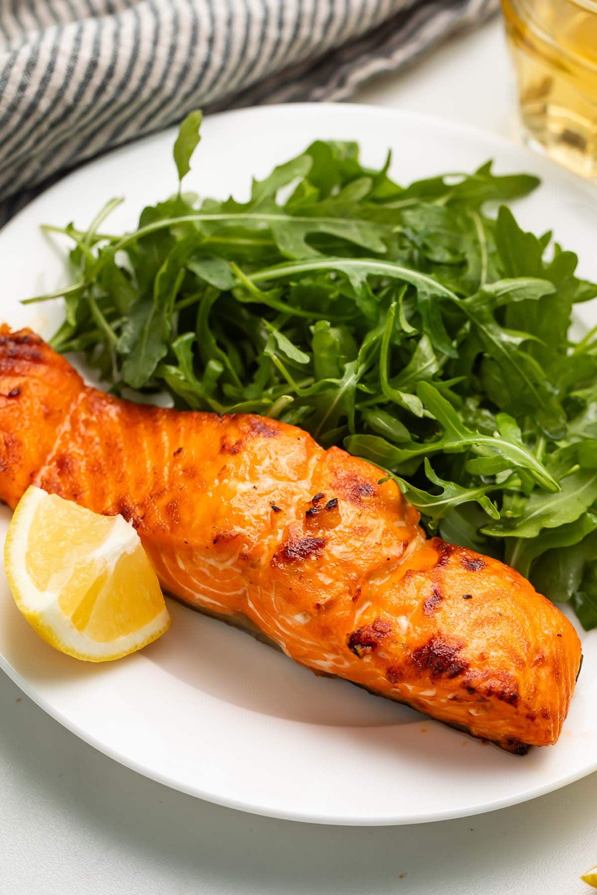 A previously-frozen salmon fillet cooked in the air fryer and served on a plate with a small side salad.