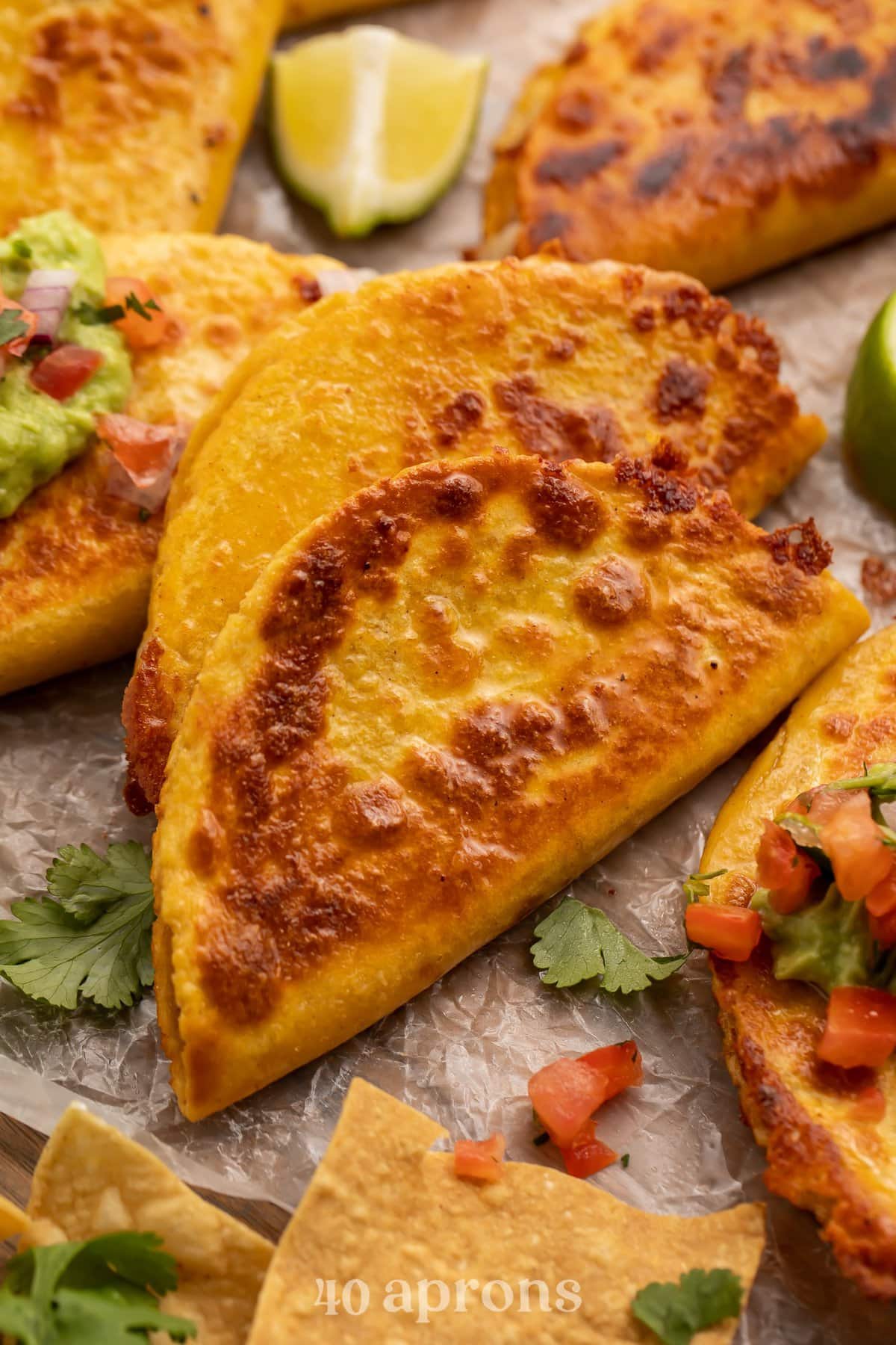 Closeup view of a crispy, cheesy, refried bean taco on parchment paper with pico and cilantro.