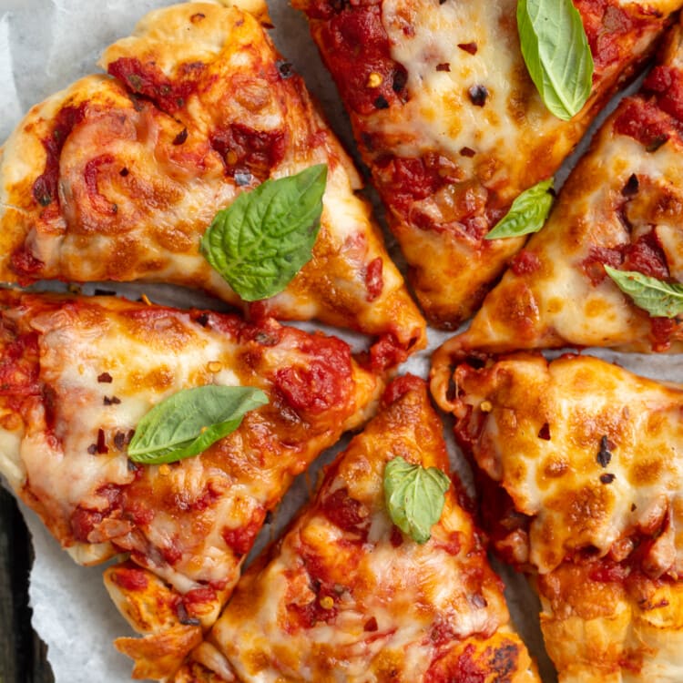 Close-up, angled view of soft and fluffy air fryer pizza on a white plate.