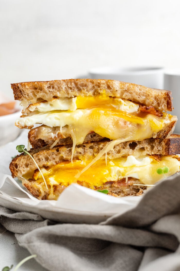 Side view of a fried egg sandwich cut in half, with one half stacked on top of the other.