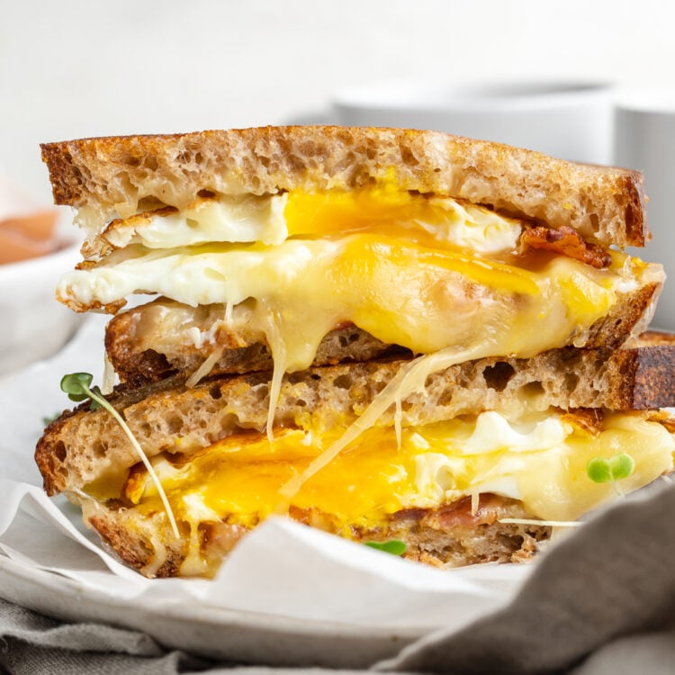 Side view of a fried egg sandwich cut in half, with one half stacked on top of the other.