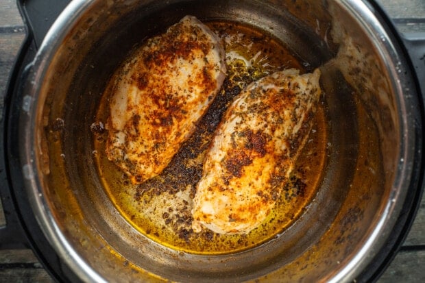 Seared chicken breasts in Instant Pot with olive oil and seasonings.