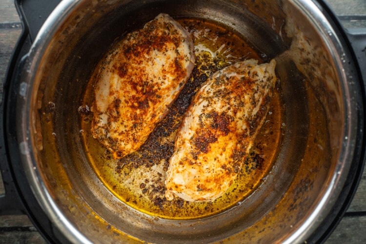 Seared chicken breasts in Instant Pot with olive oil and seasonings.