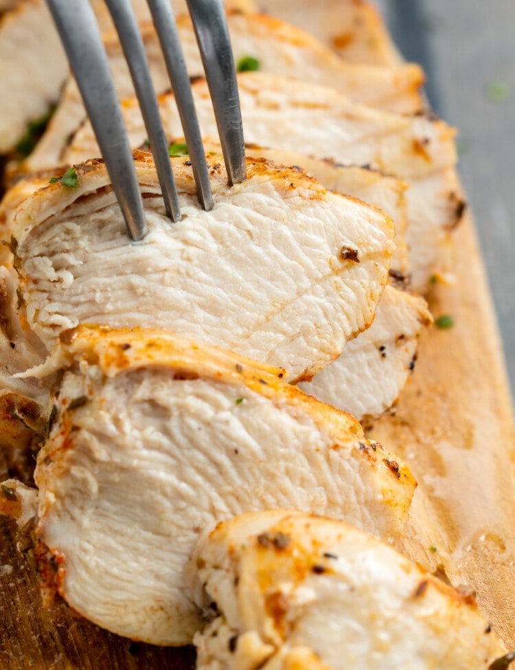 Close-up view of sliced chicken breast cooked in the Instant Pot being pierced by a fork.