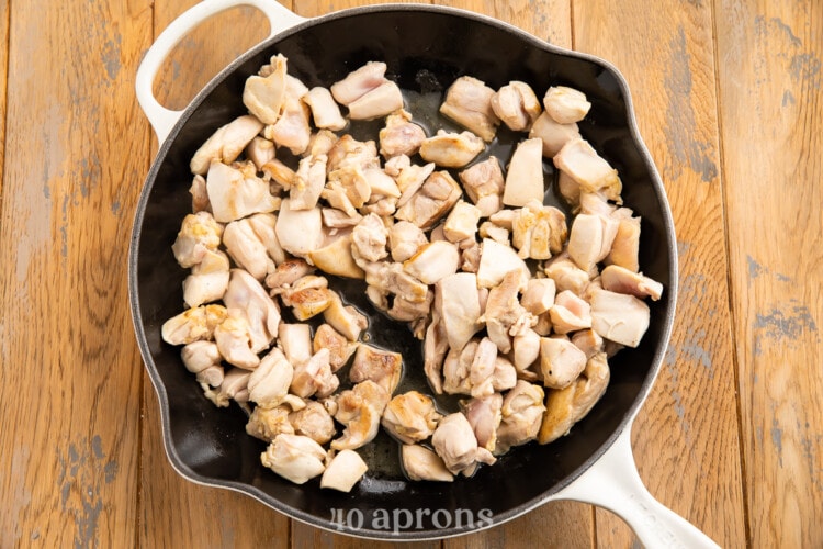 Chopped chicken thigh pieces in large skillet with neutral oil.