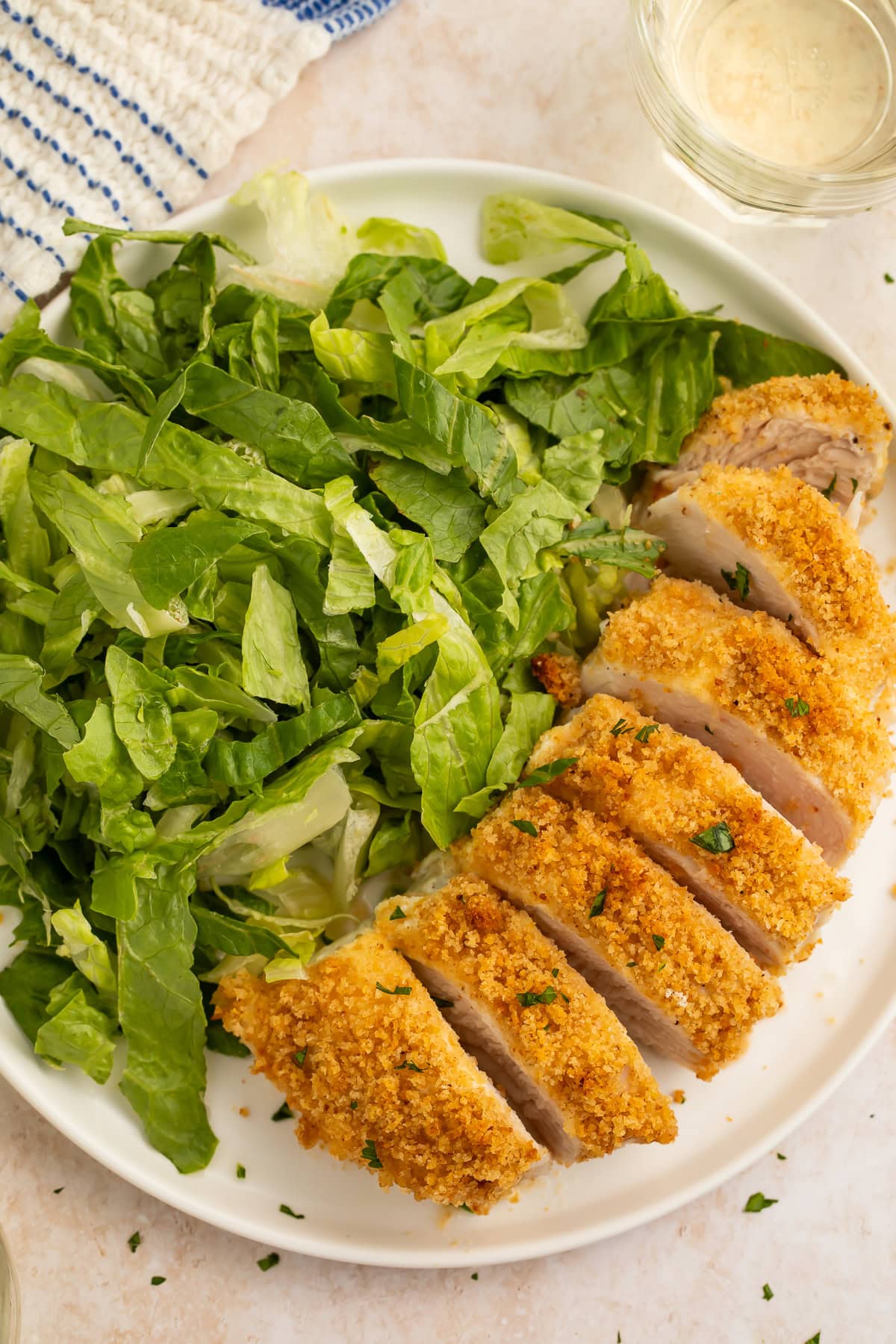 Close-up of sliced parmesan-crusted chicken breast with crispy golden breadcrumbs and fresh parsley garnish.