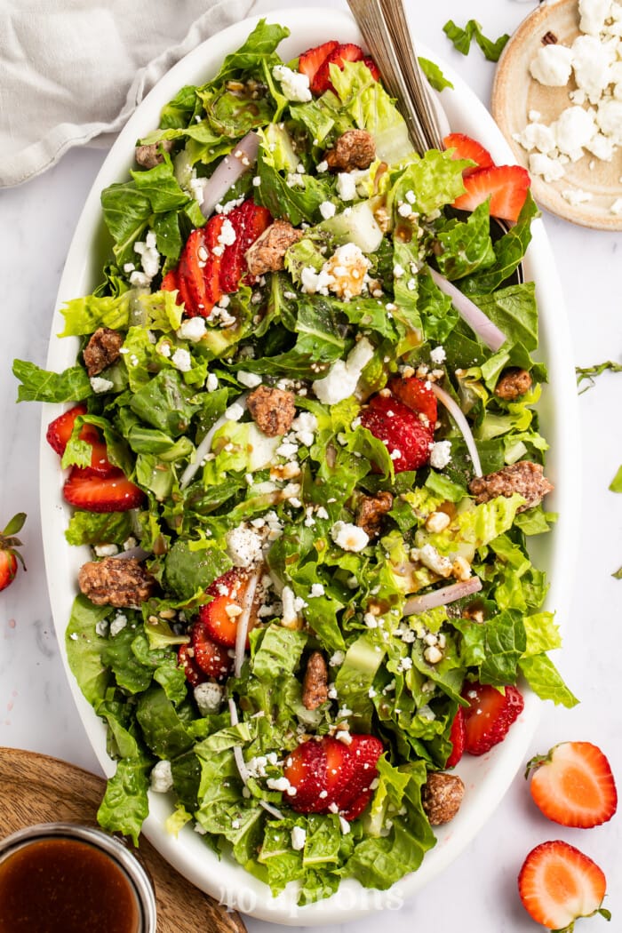 Overhead view of a long oval salad boat with strawberry goat cheese salad and balsamic vinaigrette.