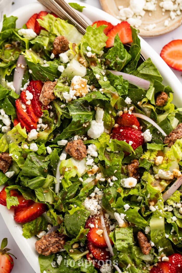 Close-up, overhead view of strawberry goat cheese salad with goat cheese crumbles and praline pecans.