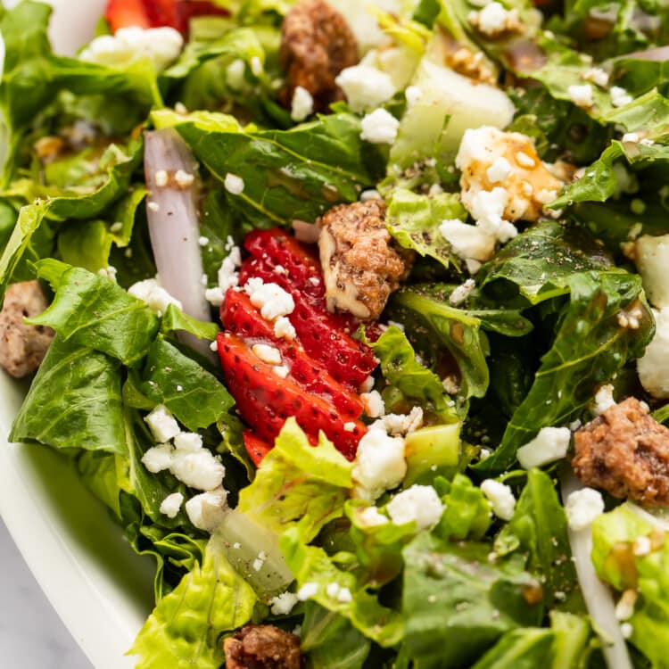 Close-up, angled photo showing strawberry goat cheese salad in an oval salad dish.