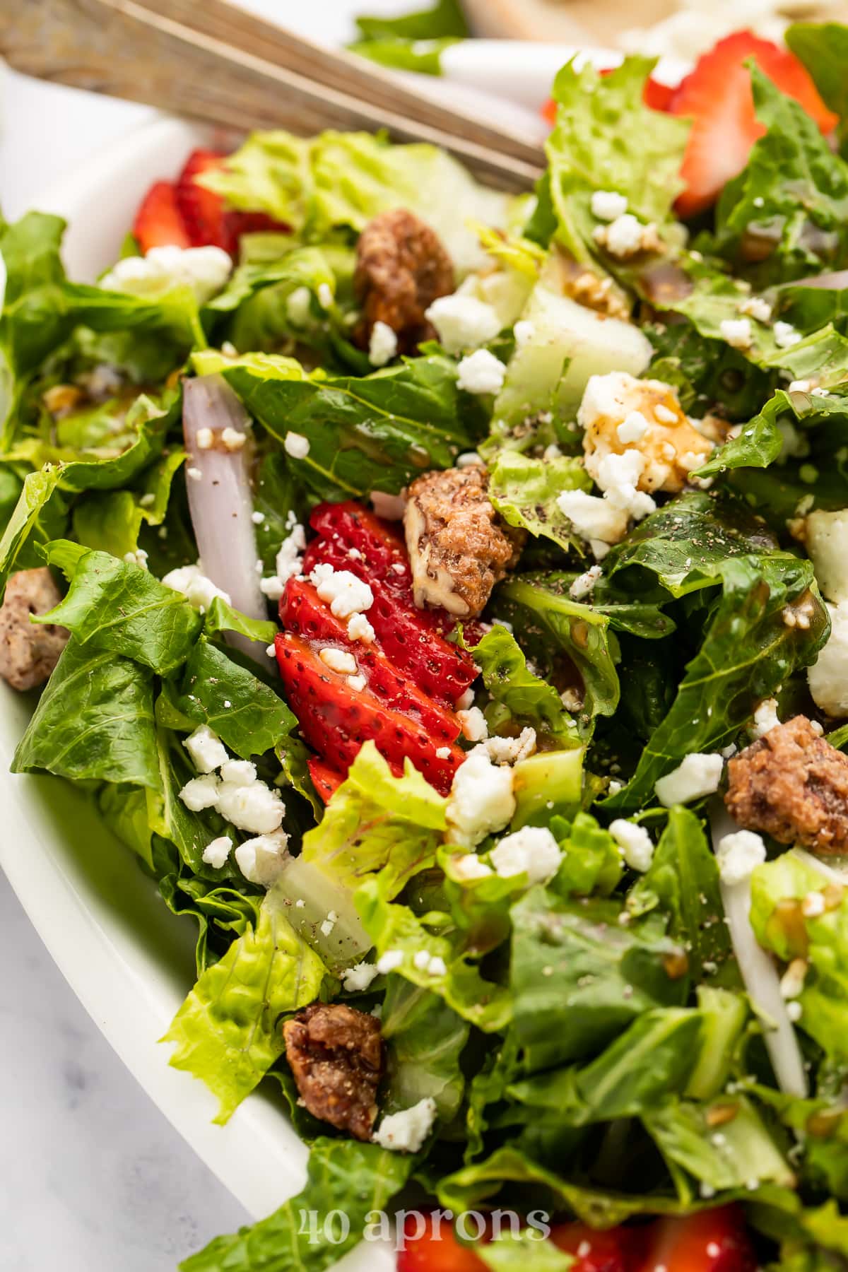 Close-up, angled photo showing strawberry goat cheese salad in an oval salad dish.