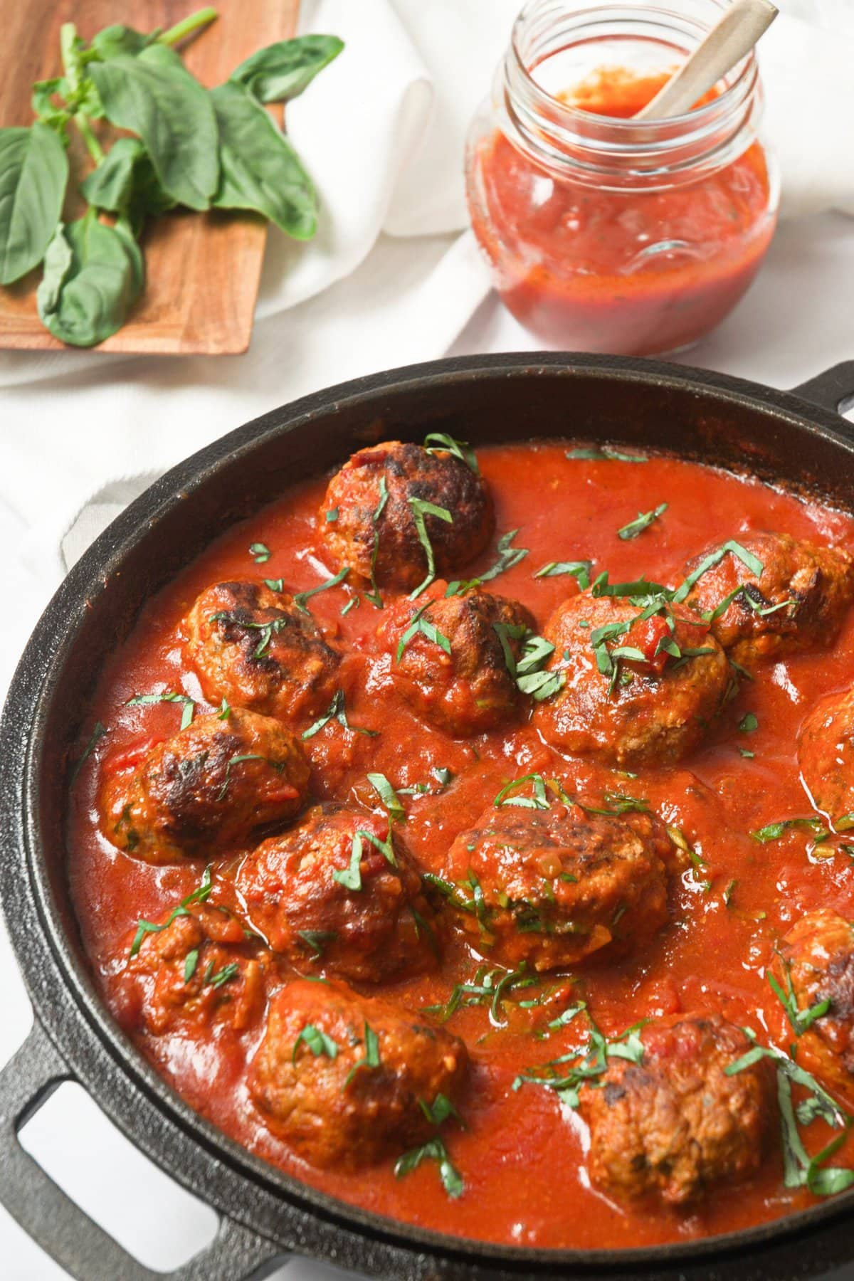 Whole30 Italian meatballs in a cast-iron skillet with marinara sauce.