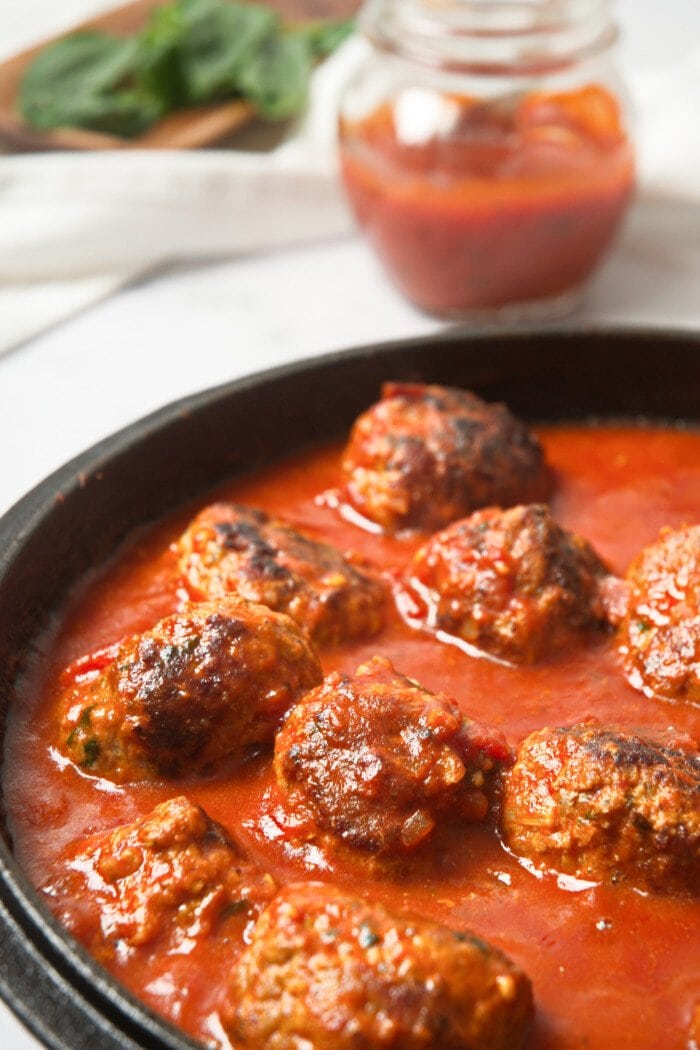 Whole30 Italian meatballs in a cast-iron skillet with marinara sauce.