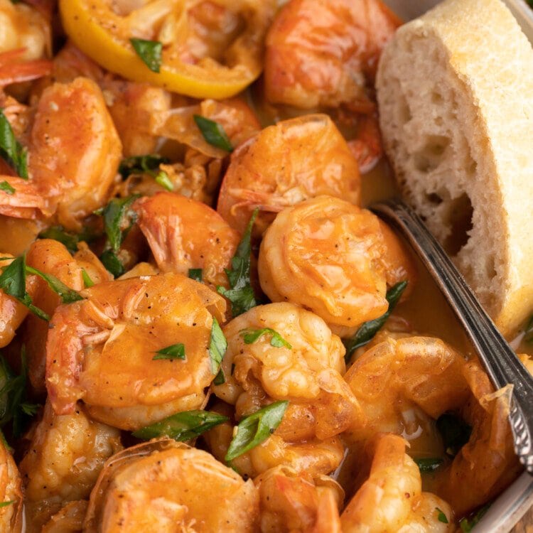 Overhead view of a bowl of BBQ shrimp with crusty bread.