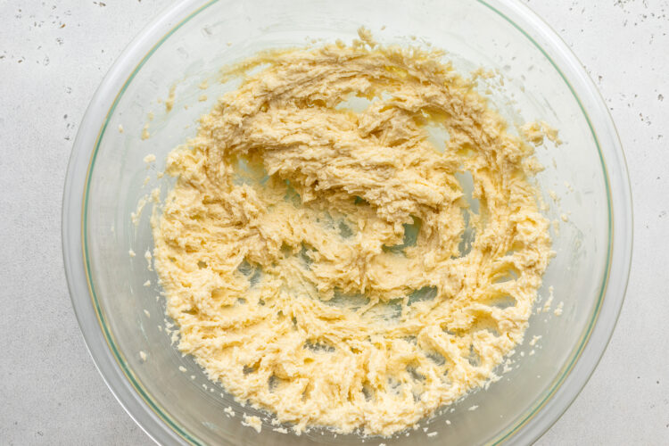 Overhead view of creamed butter and sugar in a large glass mixing bowl.