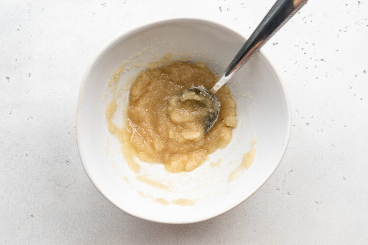 Overhead view of lemon drizzle topping in a small mixing bowl with a spoon.